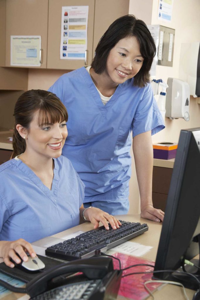 Two female nurses working on computer in doctor's office