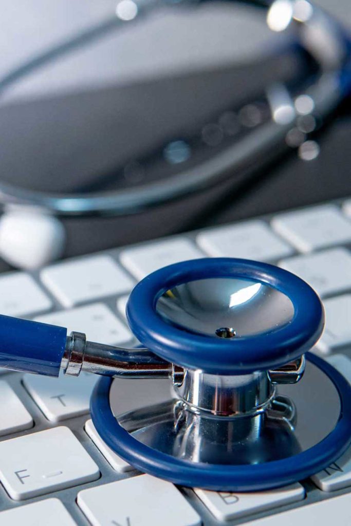 Medical science technology concept. Blue stethoscope on white modern keyboard on doctor desk. Health and wellness background. Global healthcare business. Computer antivirus protection